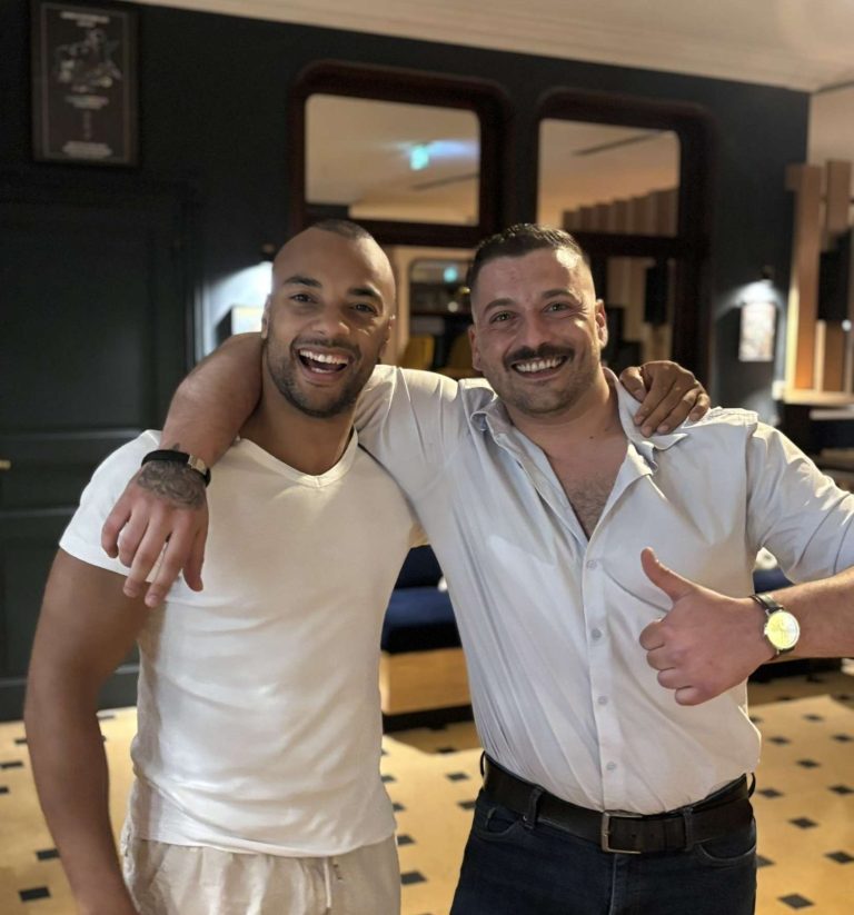 Deux hommes souriants posent ensemble, l'un faisant un pouce en l'air.